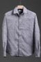 Men's grey long sleeve dress shirt with abstract pattern, featuring a spread collar and button-down front, hanging on a wooden hanger against a dark background.